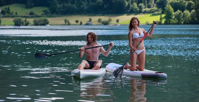 Ein junges Paar beim Stand-up-Paddling auf einem Schweizer See