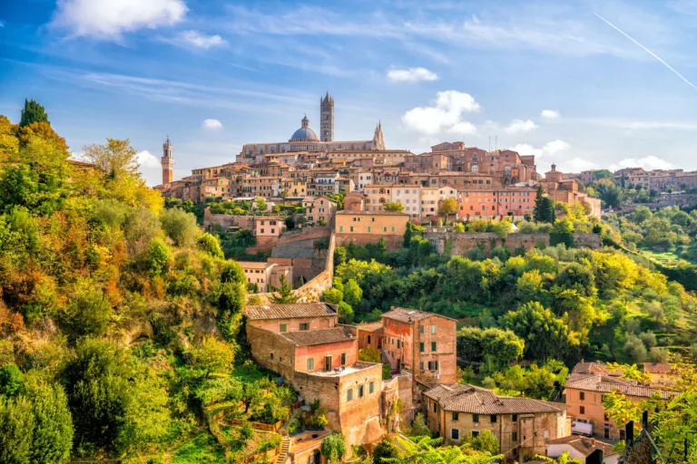 Skyline der italienischen Stadt Siena in der Toscana. Mittelalterliche Gebäude auf einem Hügel vor blauem Himmel